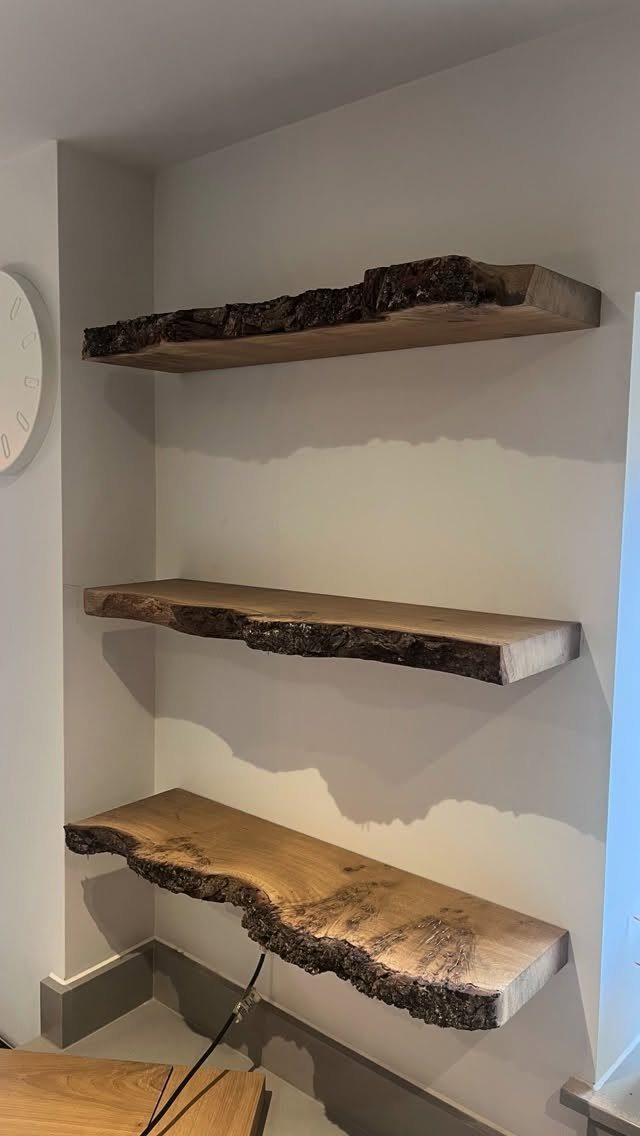 Three live-edge wooden floating shelves mounted on a neutral white wall.