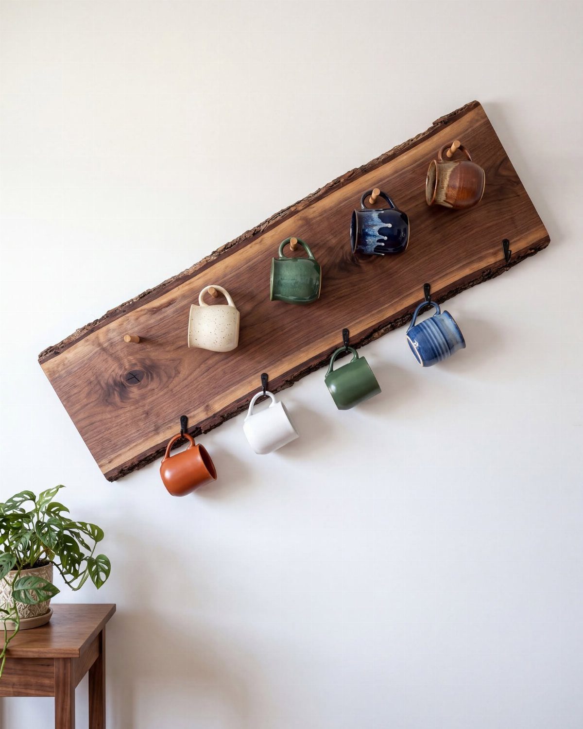 Live-edge wooden shelf with colorful ceramic mugs hanging on a white wall.