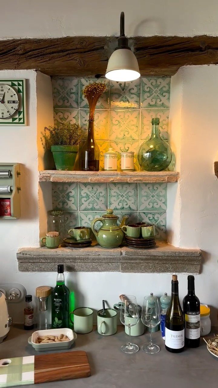 Rustic stone and wood kitchen shelves with green ceramics and glass bottles.