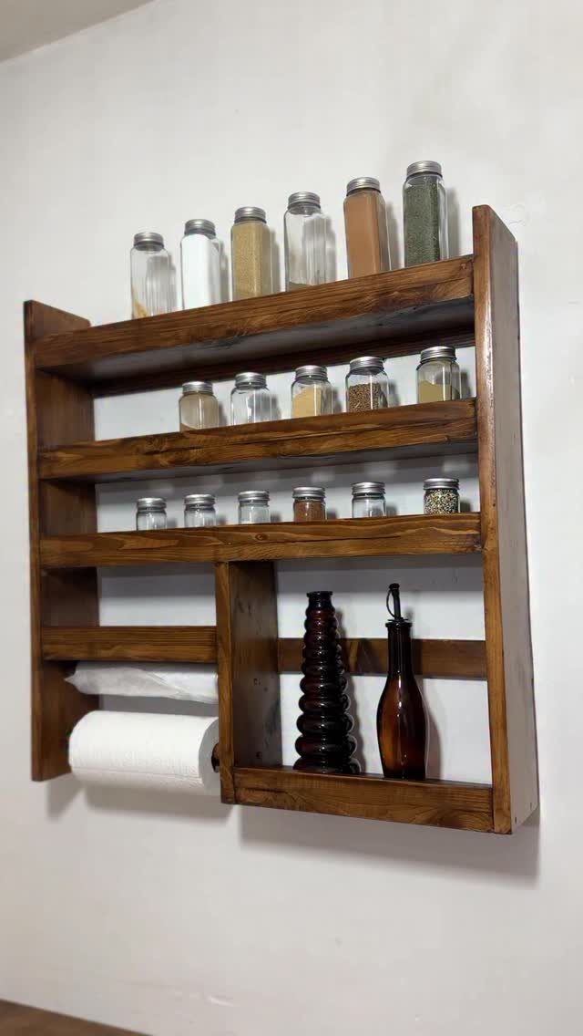 Dark brown wooden rustic kitchen shelves holding spice jars and paper towels.