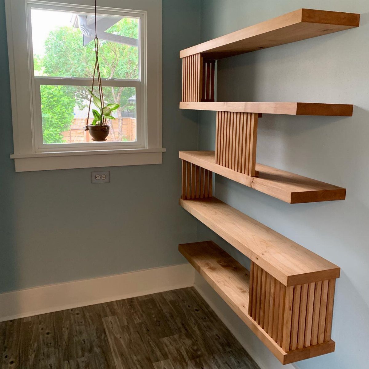 Wooden floating shelves with vertical slats mounted on a light blue wall.