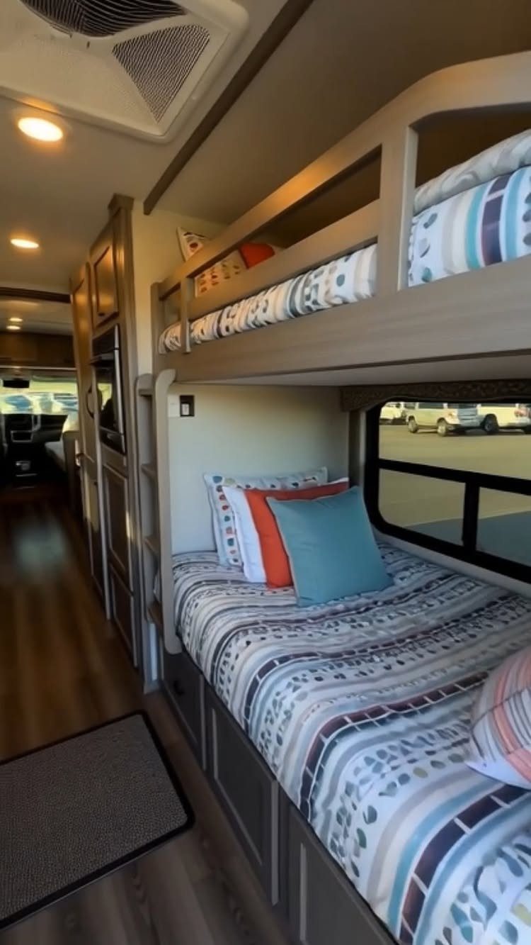 Bunk beds with blue patterned linens inside a modern recreational vehicle interior.