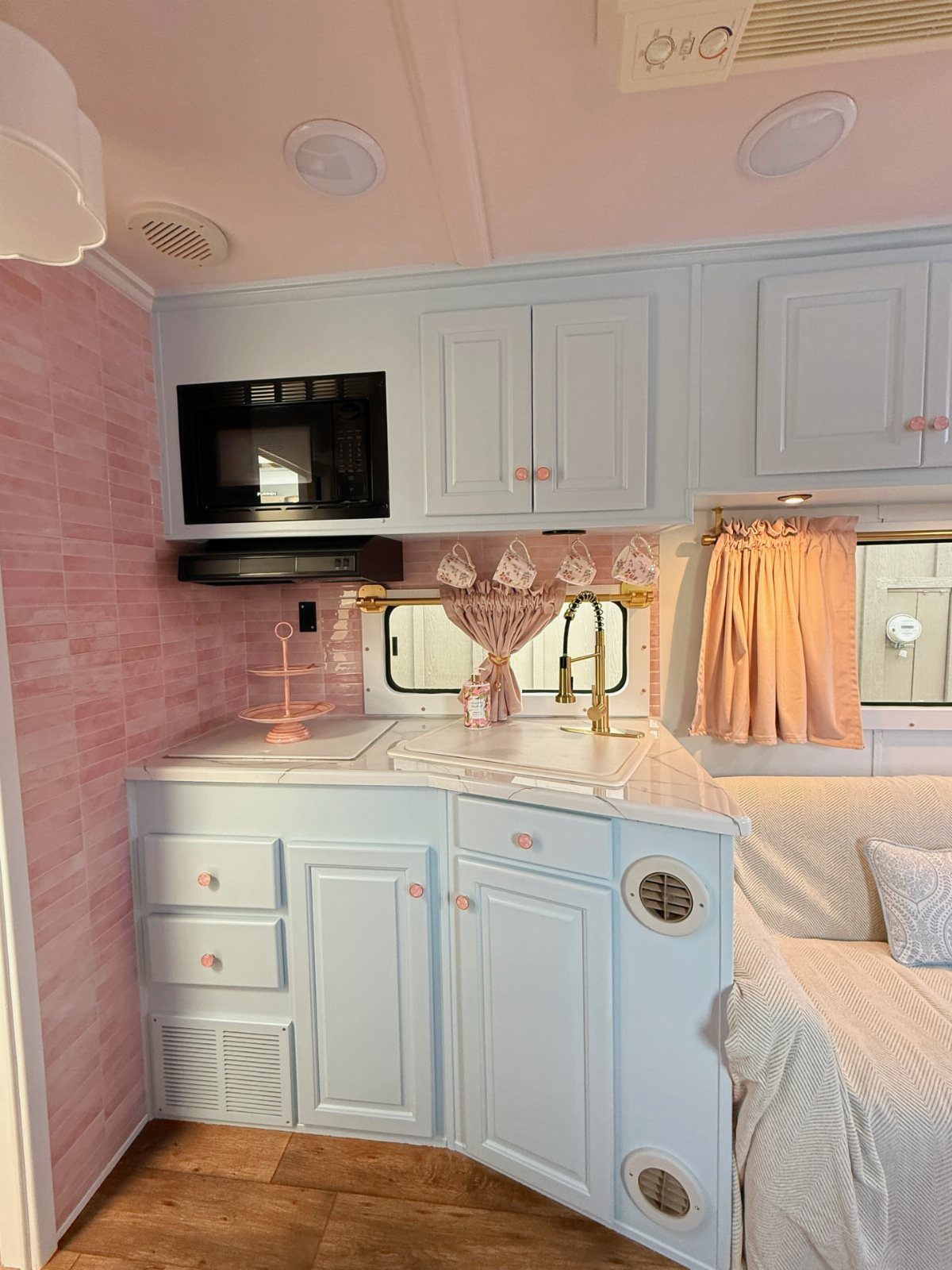 Light blue cabinets and pink walls in a remodeled RV kitchen and bedroom area.