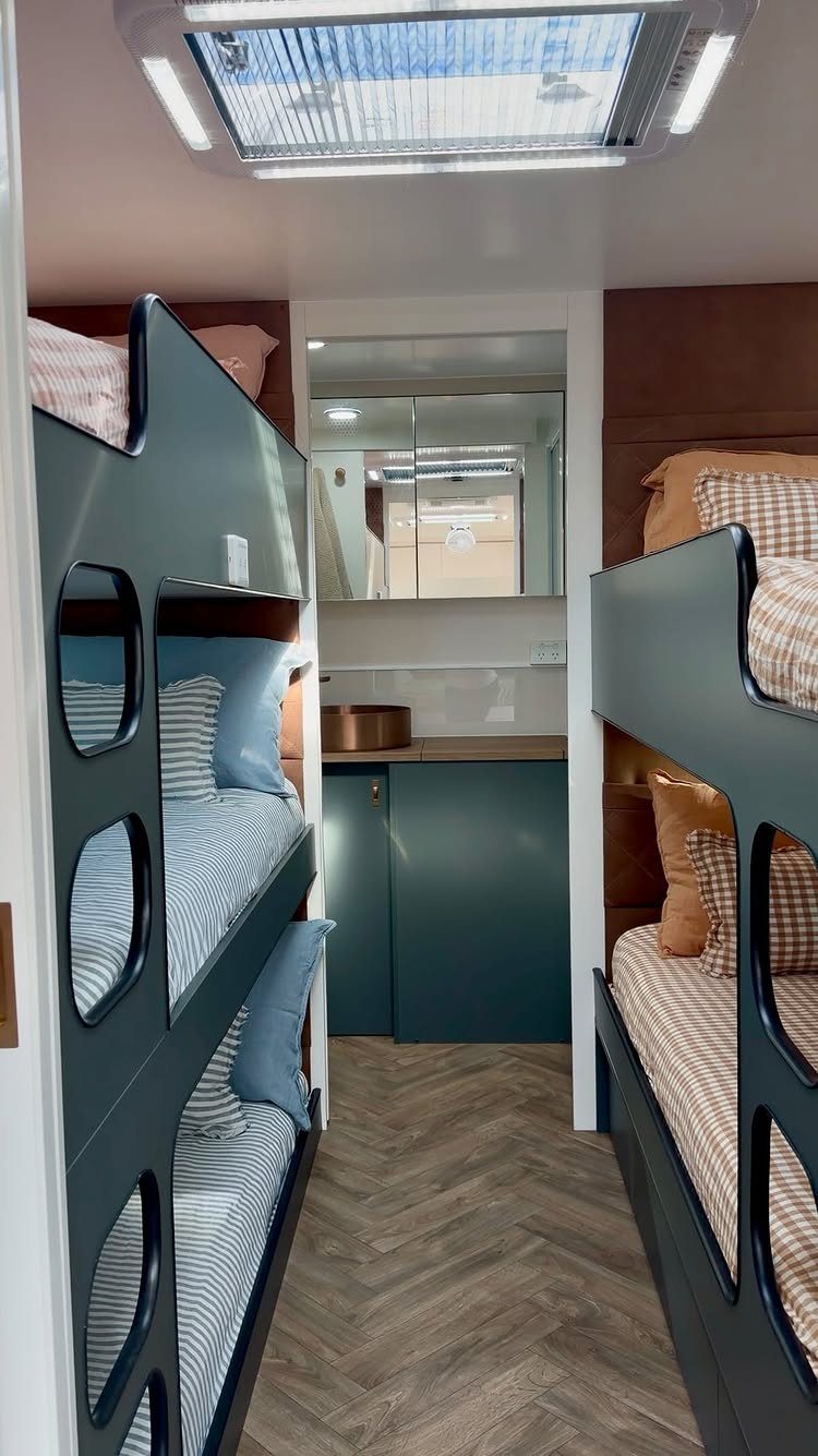 Dark teal bunk beds and wood flooring in a modern RV bedroom interior.
