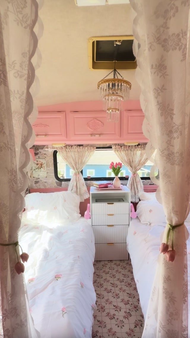 RV bedroom with twin beds, pink cabinets, and a crystal chandelier