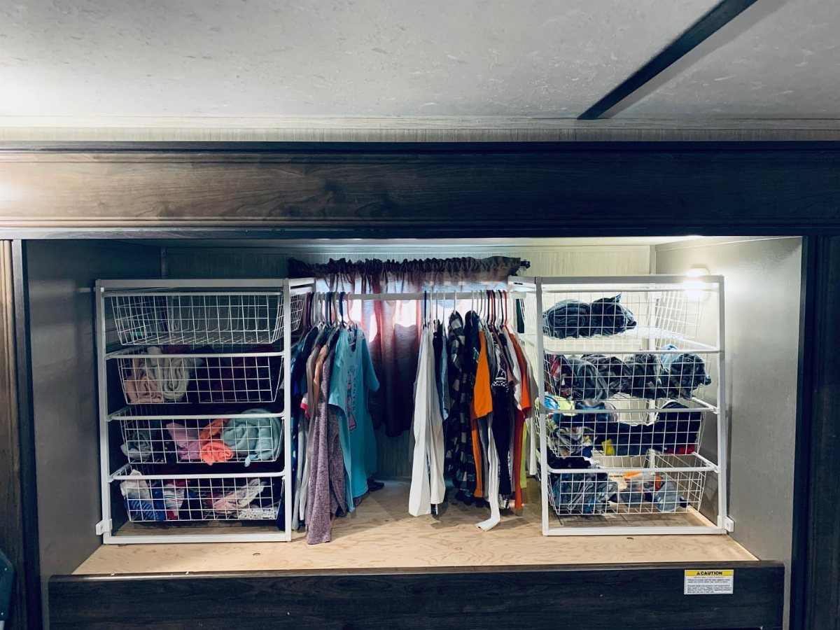 White wire storage baskets and shelving organizing clothes inside a small RV closet.