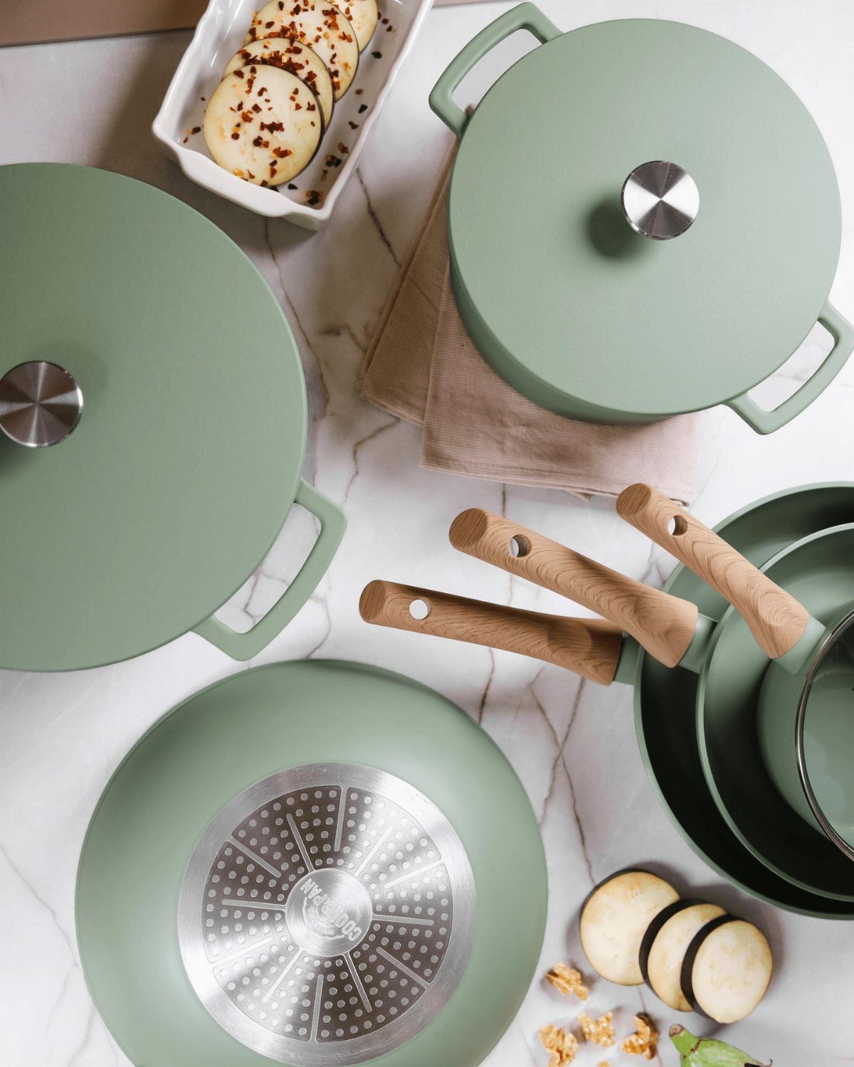 26 Sage Green Kitchen Ideas Using Wood, Brass, and Marble 15 Sage green pots and pans with wooden handles on a white marble countertop.