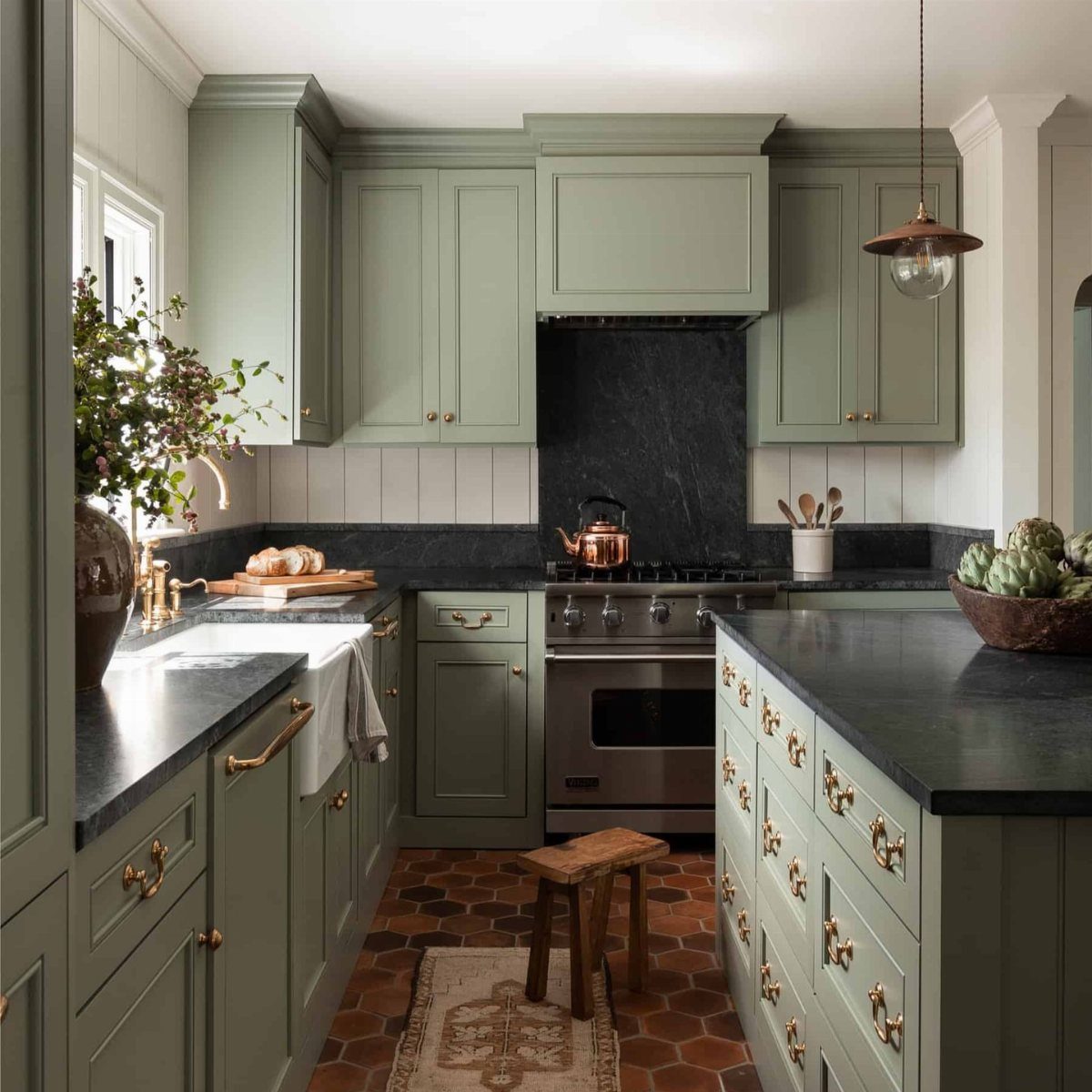 26 Sage Green Kitchen Ideas Using Wood, Brass, and Marble 11 Sage green kitchen with copper kettle, copper pendant light, and terracotta tile flooring.