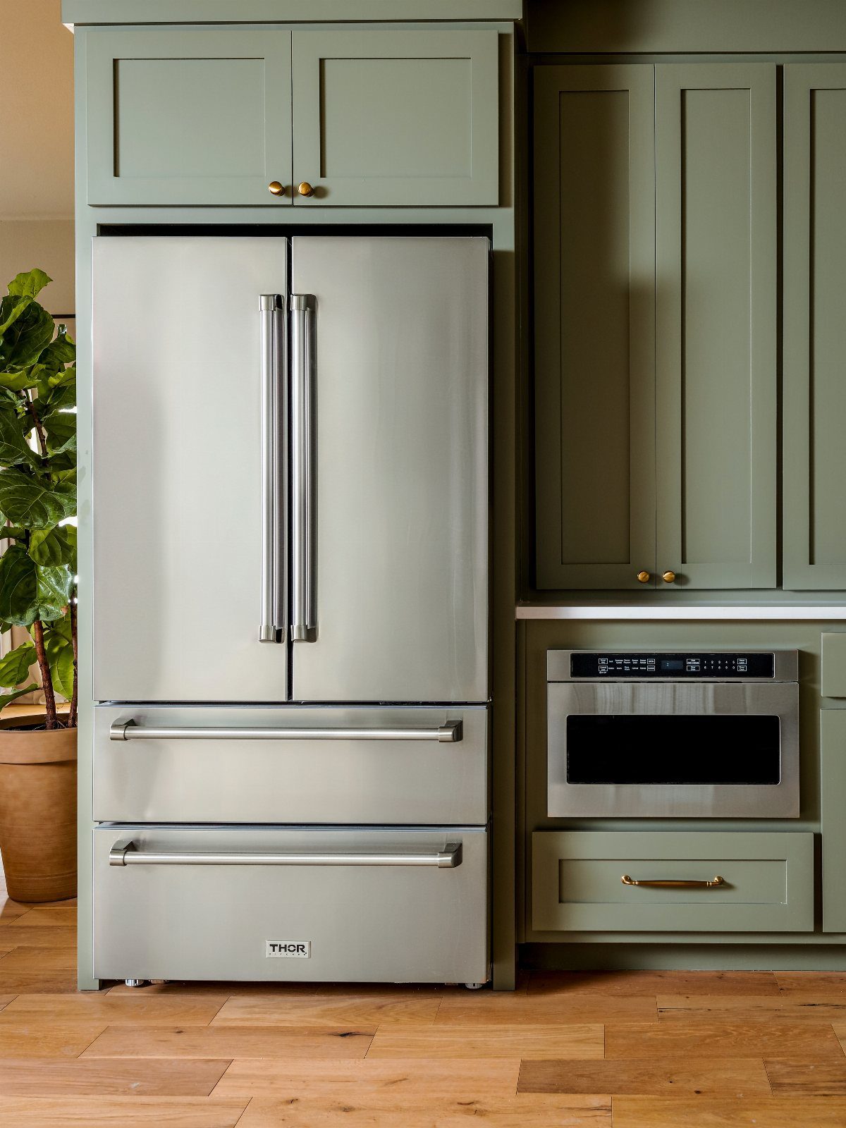 26 Sage Green Kitchen Ideas Using Wood, Brass, and Marble 18 Sage green kitchen cabinets paired with a stainless steel refrigerator and built-in microwave.