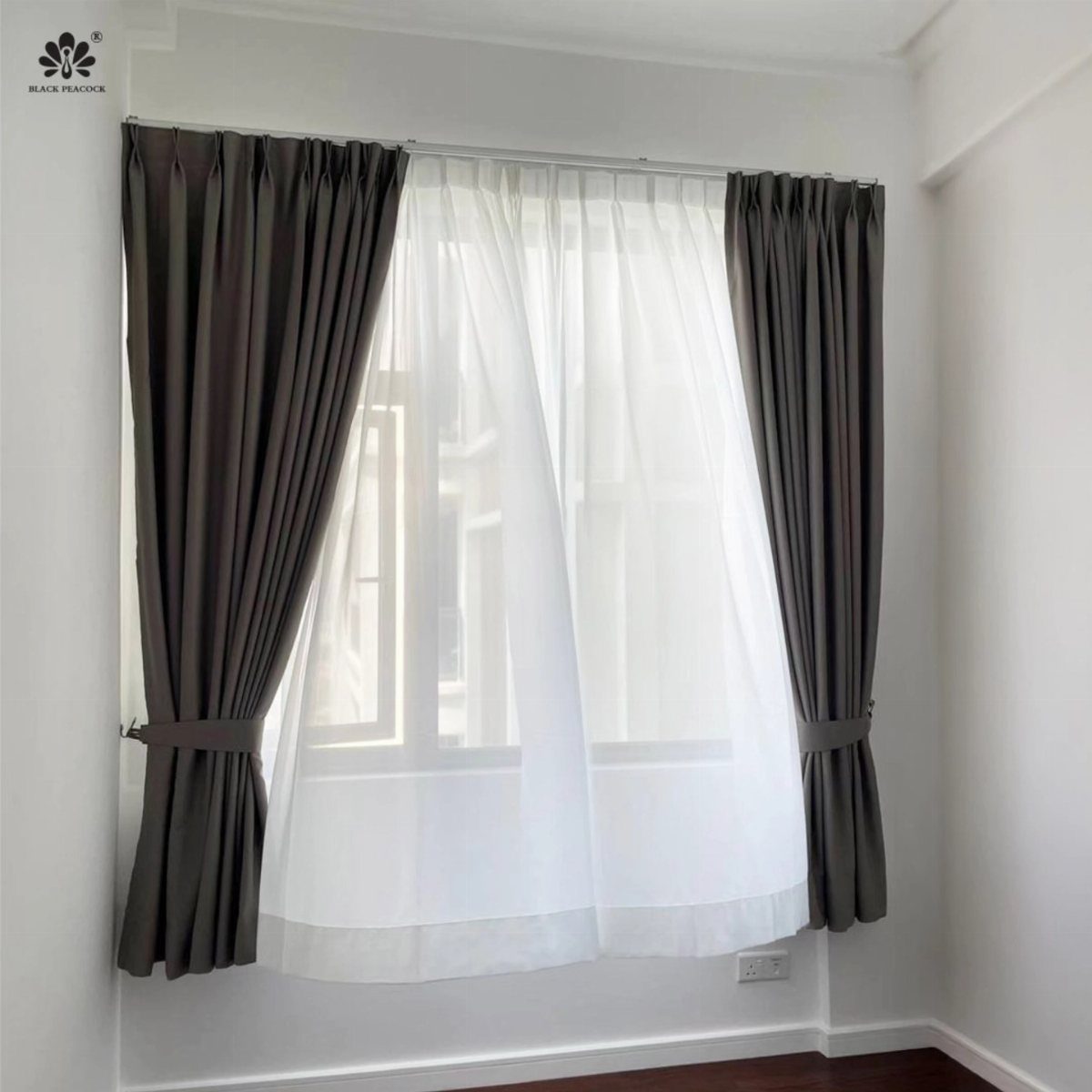 Grey and white short curtains hanging over a window in a bright room.