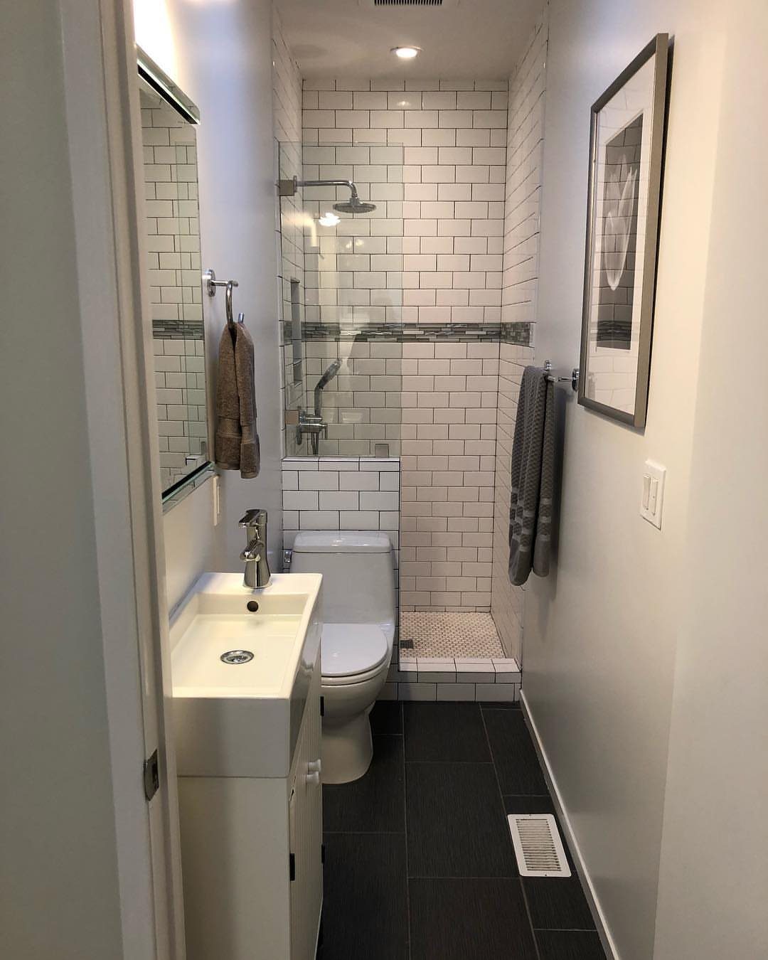 Small white sink and toilet in a narrow bathroom with white subway tiles.