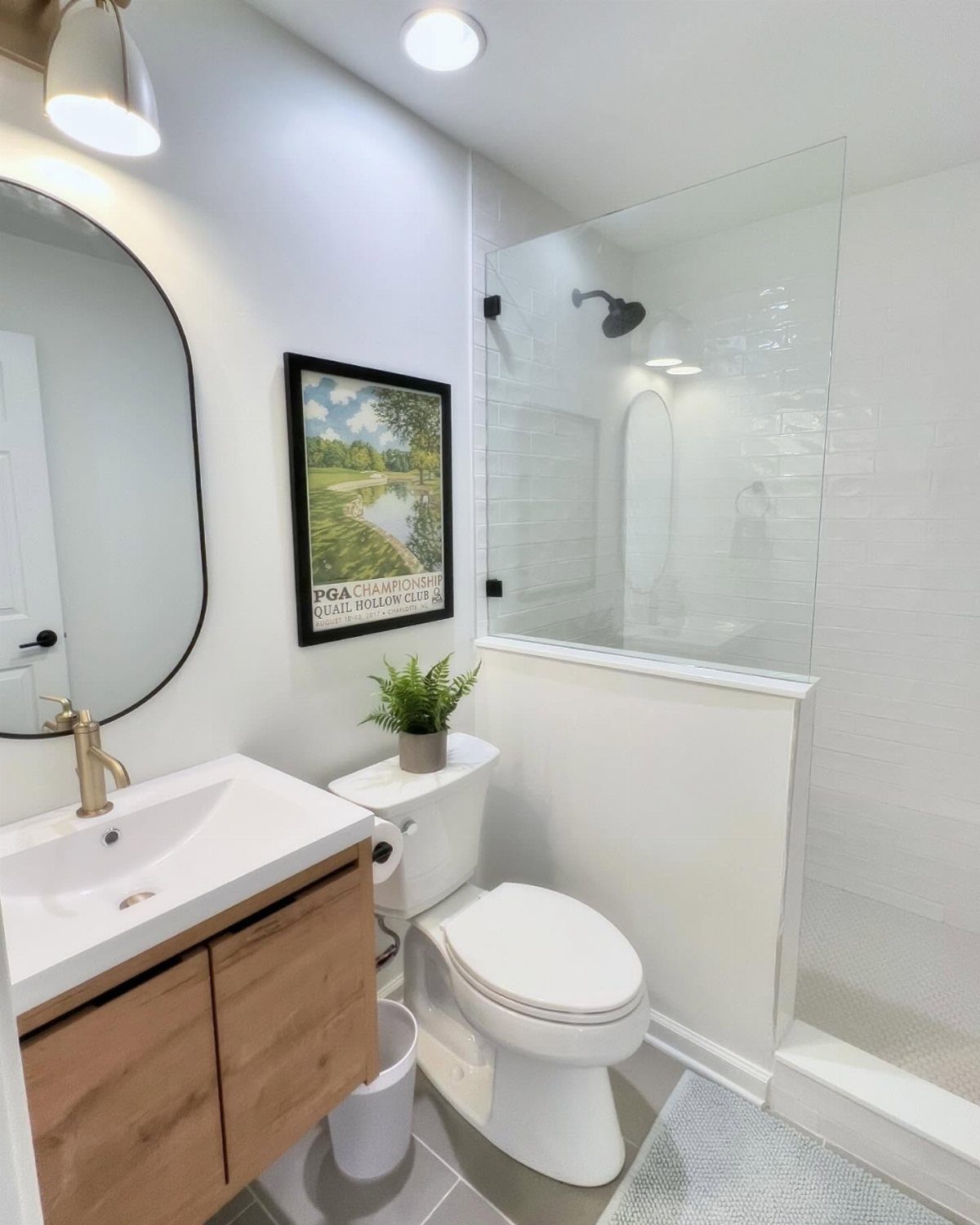 Walk-in shower with a single glass panel in a small white modern bathroom.