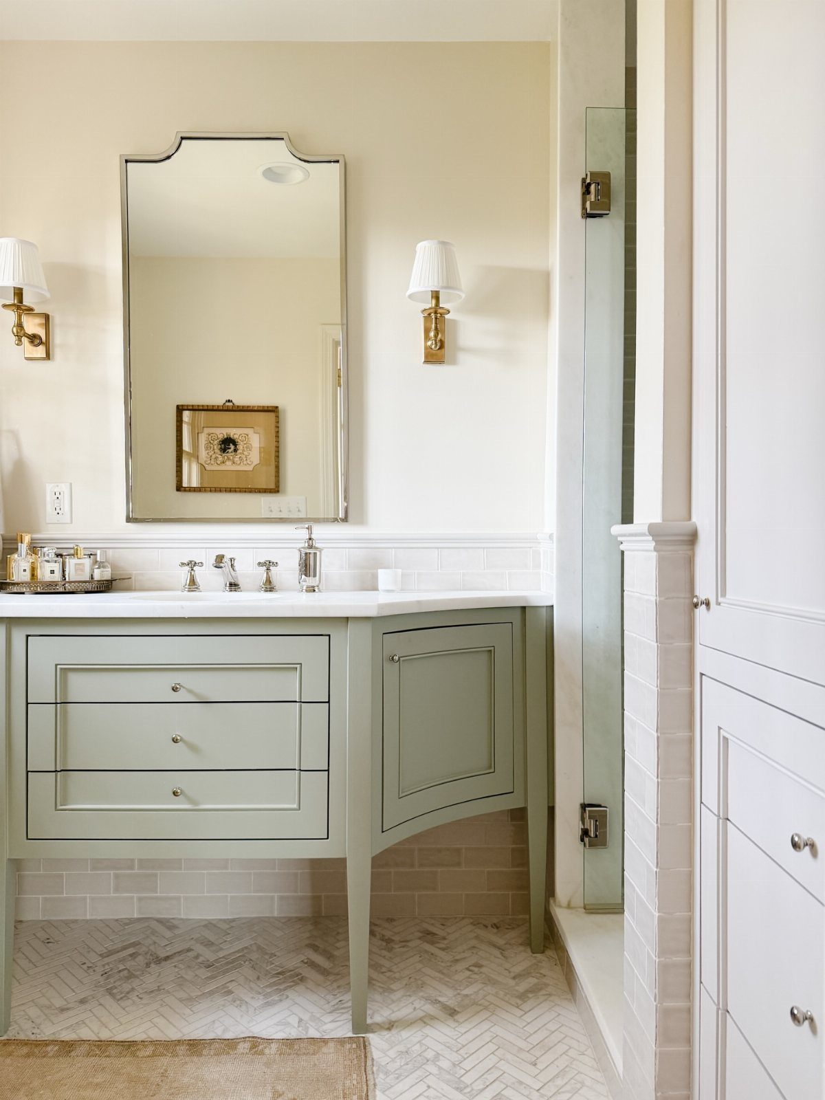 Sage green bathroom vanity with white countertop and large arched mirror.