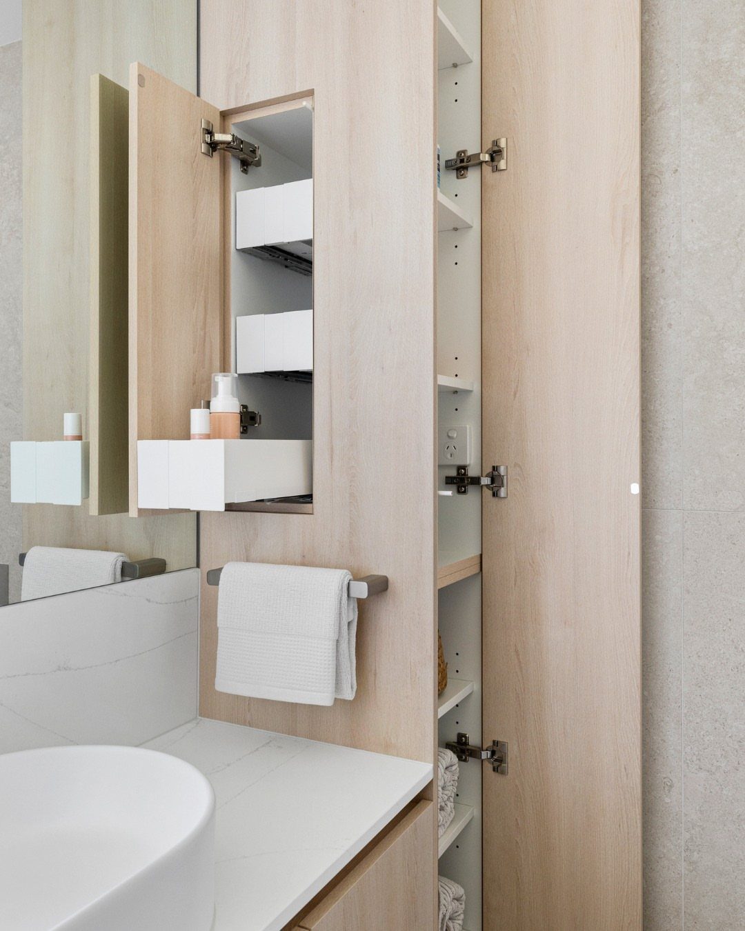 Light wood bathroom vanity with a white pull-out organizer holding toiletries inside.