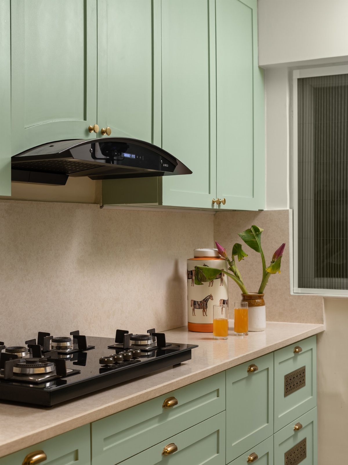 UK Kitchen Ideas Green: 21 Cabinet, Tile and Worktop Looks 1 Mint green kitchen cabinets with gold hardware and a black gas stovetop.