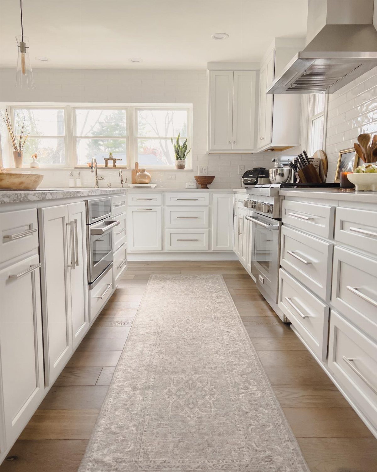 Light grey patterned runner rug on wood floor in a white kitchen